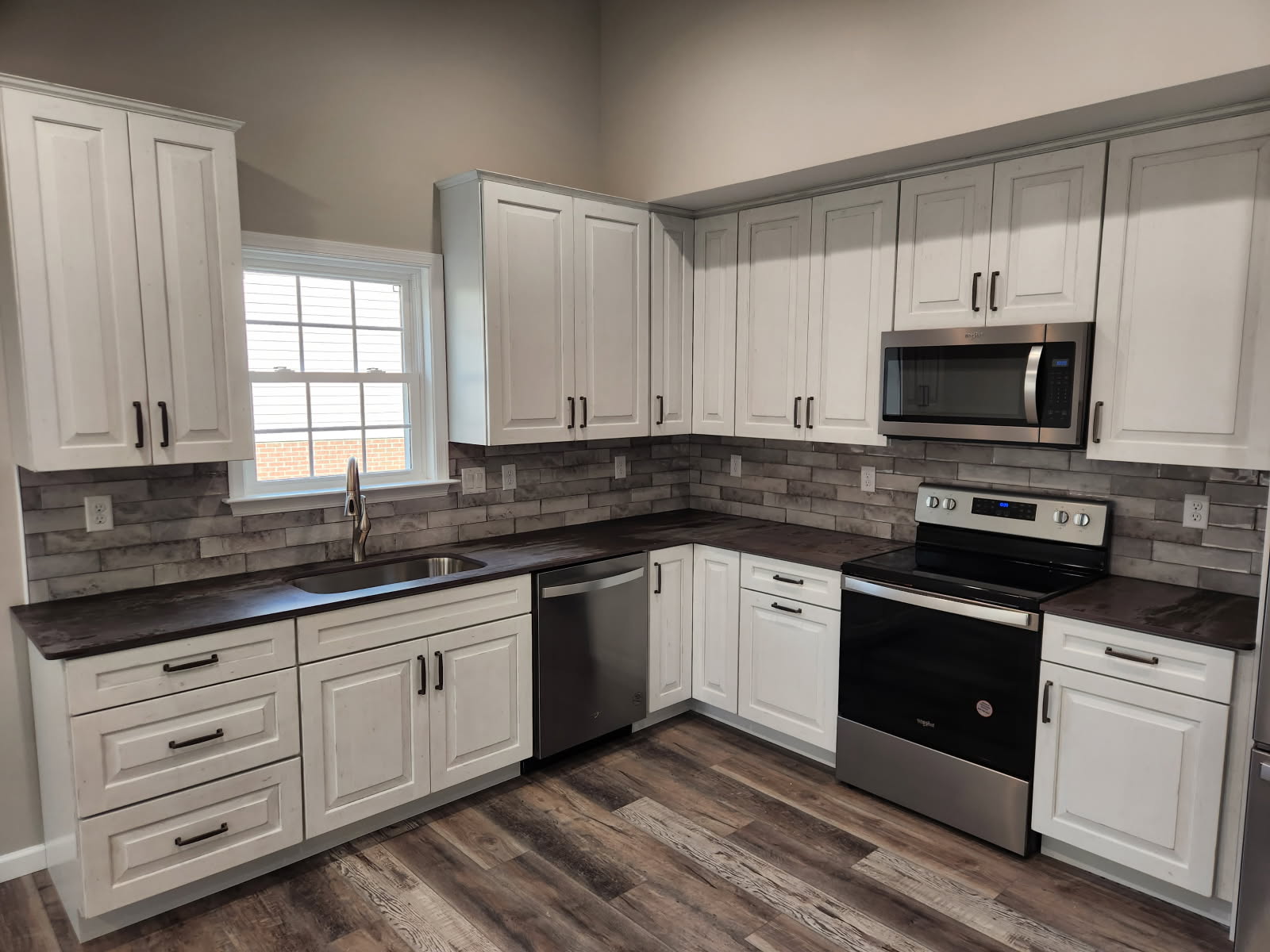 Kitchen with white cabinets, a brick backsplash, and stainless appliances