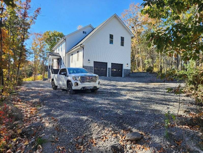 White farmhouse with an attached garage and a driveway
